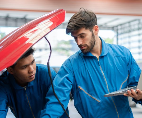 car-mechanic-team-using-laptop-boosting-car-engine-at-auto-repair-shop.jpg